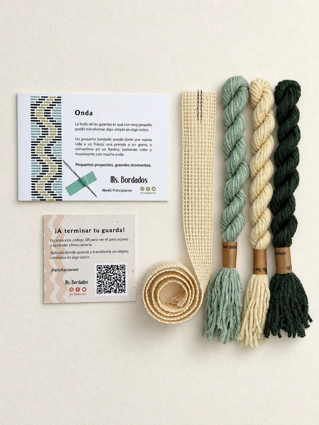 Componentes del Kit Franja Onda Pradera (formato Guarda larga): cañamazo de 75 × 5 cm, lanas 100% uruguayas en Amarillo, Verde y Verde agua, aguja, manual impreso y tarjeta con el QR del video para terminar tu guarda — Ms. Bordados