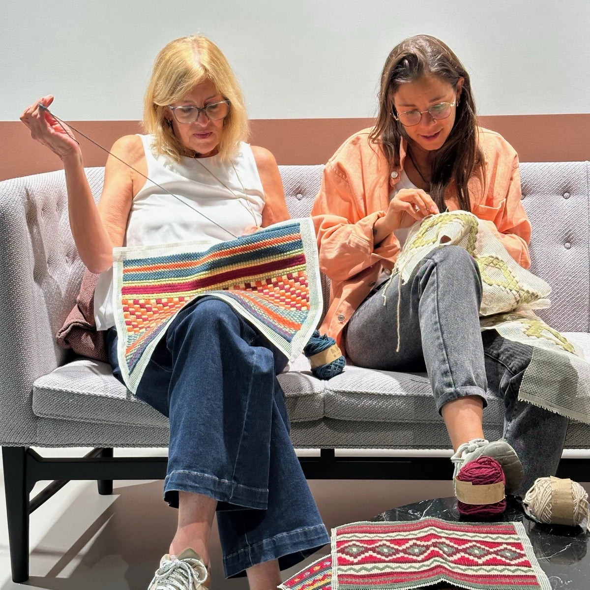 Clase en vivo de bordado sobre cañamazo: dos personas bordando en un sillón — Ms. Bordados