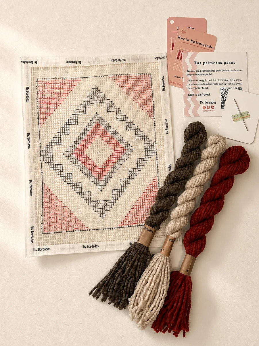 Componentes del Kit Cuadrito Greca: cañamazo con el diseño, lanas en rojo, marrón y beige, aguja y tarjetas de puntadas — Ms. Bordados