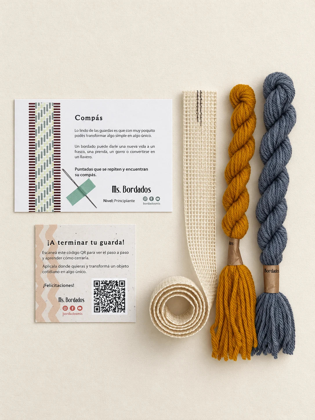 Componentes del Kit Franja Compás Provenza (formato Guarda larga): cañamazo de 75 × 5 cm, lanas 100% uruguayas en Celeste y Amarillo, aguja, manual impreso y tarjeta con el QR del video para terminar tu guarda — Ms. Bordados