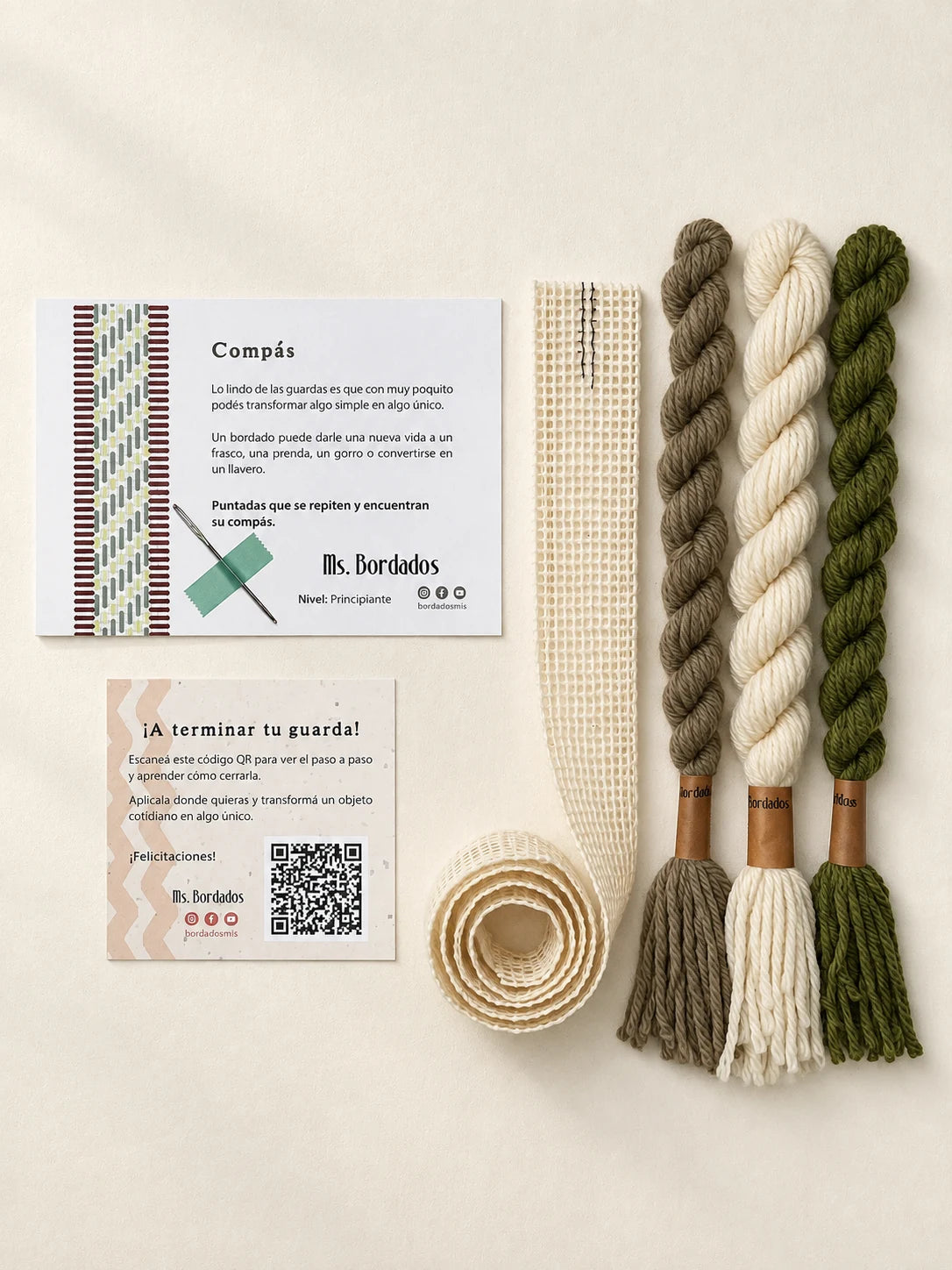 Componentes del Kit Franja Compás Salvia (formato Guarda larga): cañamazo de 75 × 5 cm, lanas 100% uruguayas en Crudo, Verde seco y Taupe, aguja, manual impreso y tarjeta con el QR del video para terminar tu guarda — Ms. Bordados