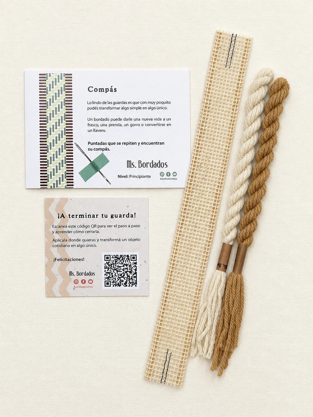 Componentes del Kit Franja Compás Sol (formato Guarda corta): cañamazo de 30 × 5 cm, lanas 100% uruguayas en Crudo y Dijon, aguja, manual impreso y tarjeta con el QR del video para terminar tu guarda — Ms. Bordados