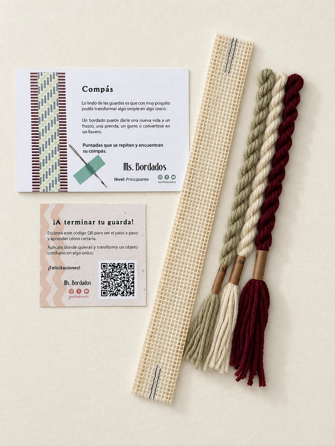 Componentes del Kit Franja Compás Viñedo (formato Guarda corta): cañamazo de 30 × 5 cm, lanas 100% uruguayas en Crudo, Verde eucaliptus y Bordeaux, aguja, manual impreso y tarjeta con el QR del video para terminar tu guarda — Ms. Bordados