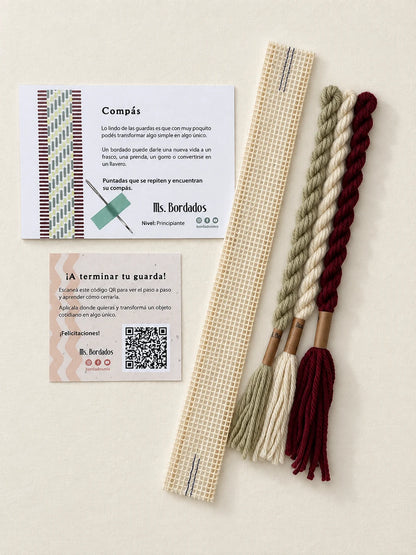 Componentes del Kit Franja Compás Viñedo (formato Guarda corta): cañamazo de 30 × 5 cm, lanas 100% uruguayas en Crudo, Verde eucaliptus y Bordeaux, aguja, manual impreso y tarjeta con el QR del video para terminar tu guarda — Ms. Bordados