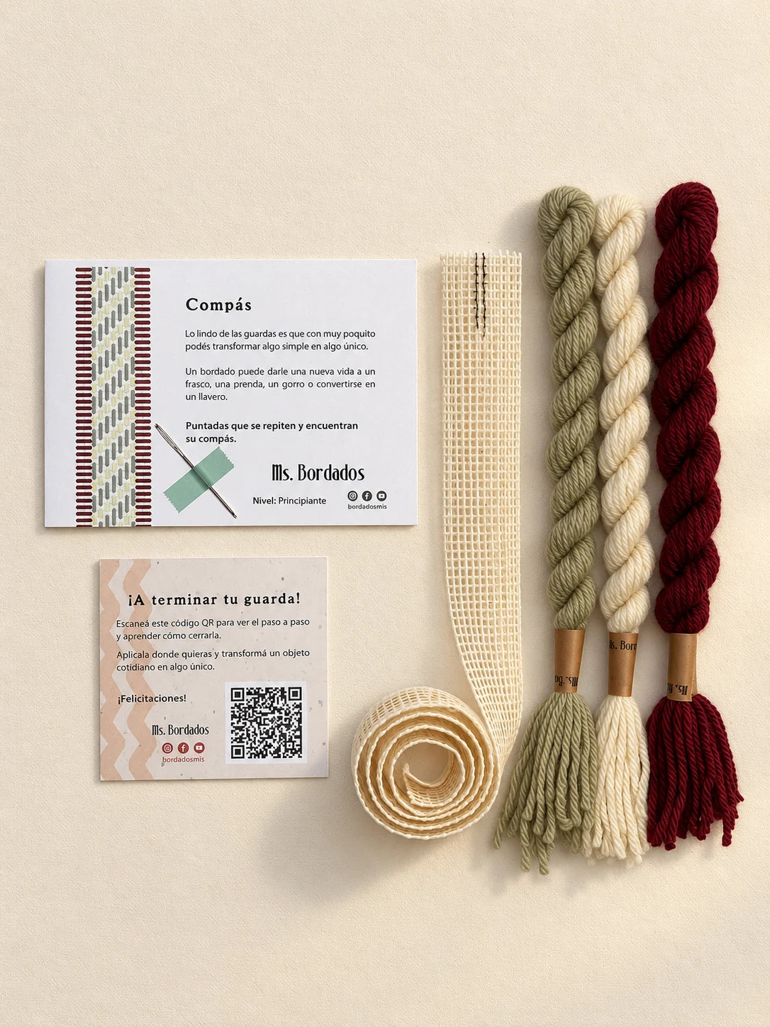 Componentes del Kit Franja Compás Viñedo (formato Guarda larga): cañamazo de 75 × 5 cm, lanas 100% uruguayas en Crudo, Verde eucaliptus y Bordeaux, aguja, manual impreso y tarjeta con el QR del video para terminar tu guarda — Ms. Bordados