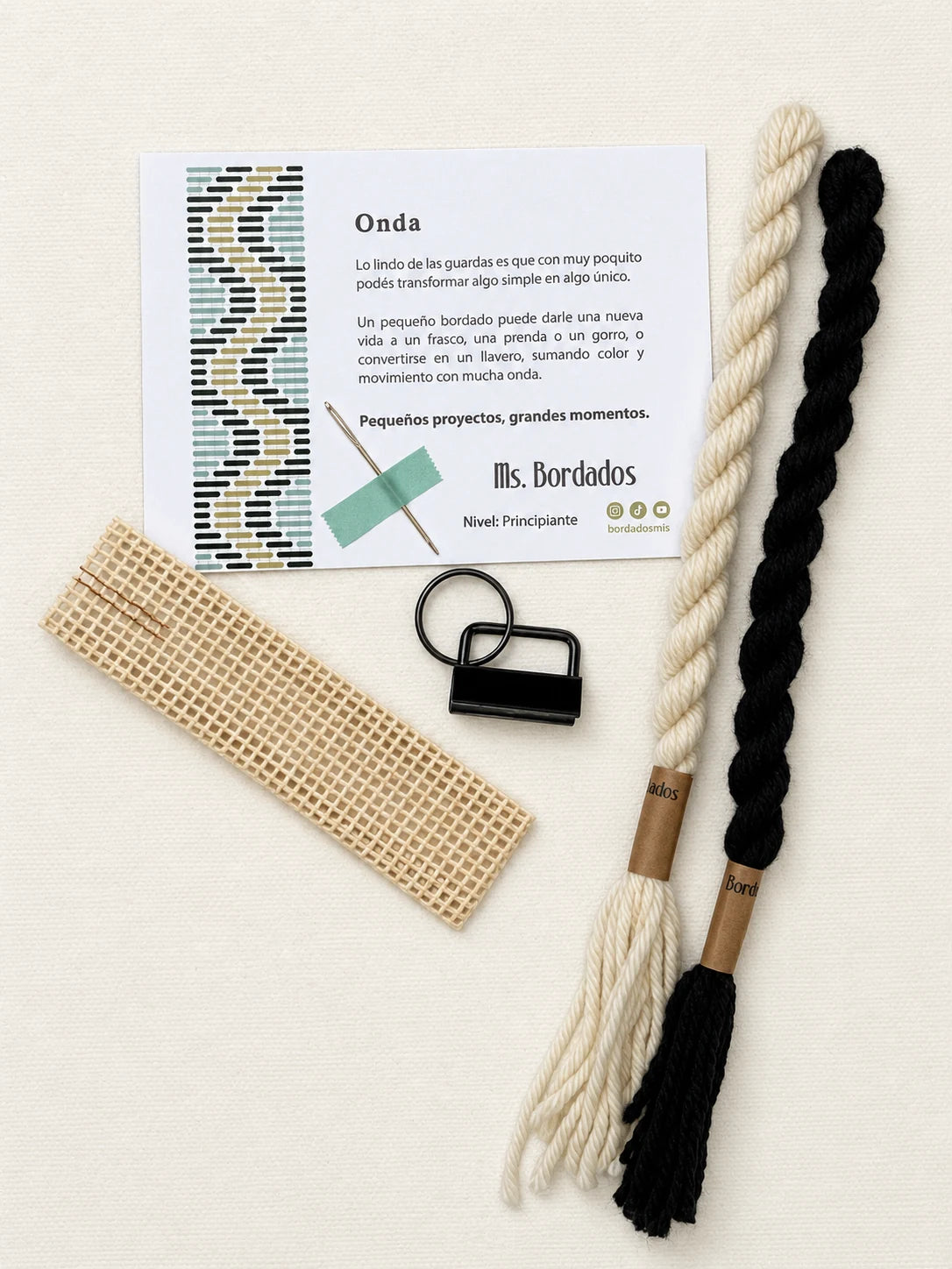 Componentes del Kit Franja Onda Cebra (formato Llavero): cañamazo, lanas 100% uruguayas en Negro y Crudo, aguja, manual impreso y herraje del llavero — Ms. Bordados