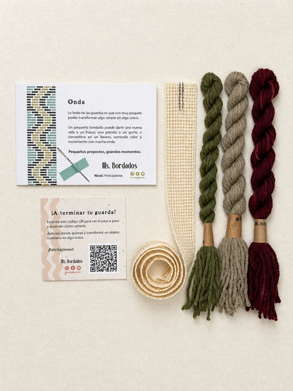 Componentes del Kit Franja Onda Huerta (formato Guarda larga): cañamazo de 75 × 5 cm, lanas 100% uruguayas en Verde seco, Verde eucaliptus y Berenjena, aguja, manual impreso y tarjeta con el QR del video para terminar tu guarda — Ms. Bordados