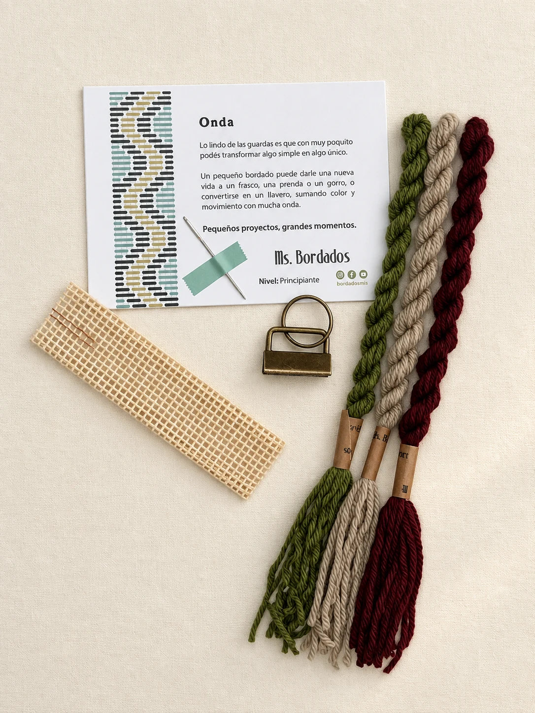 Componentes del Kit Franja Onda Huerta (formato Llavero): cañamazo, lanas 100% uruguayas en Verde seco, Verde eucaliptus y Berenjena, aguja, manual impreso y herraje del llavero — Ms. Bordados
