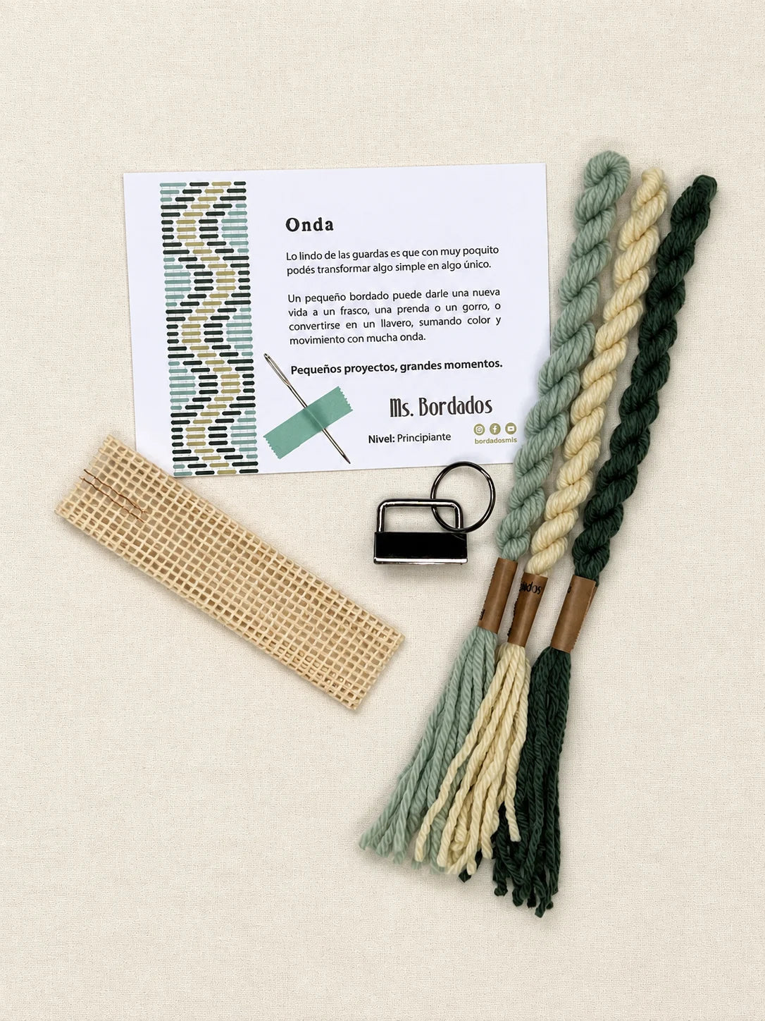Componentes del Kit Franja Onda Pradera (formato Llavero): cañamazo, lanas 100% uruguayas en Amarillo, Verde y Verde agua, aguja, manual impreso y herraje del llavero — Ms. Bordados