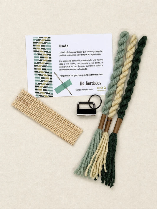 Componentes del Kit Franja Onda Pradera (formato Llavero): cañamazo, lanas 100% uruguayas en Amarillo, Verde y Verde agua, aguja, manual impreso y herraje del llavero — Ms. Bordados