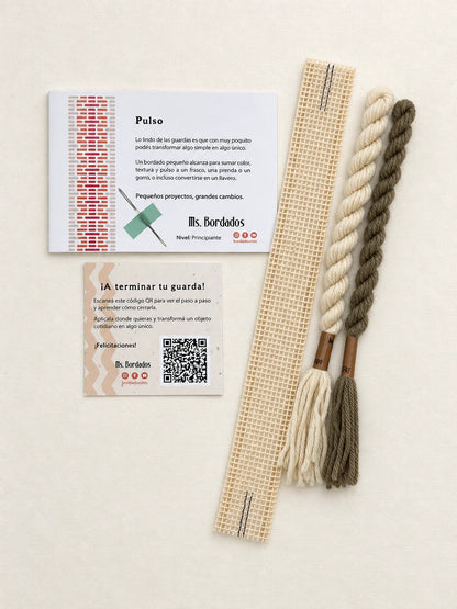 Componentes del Kit Franja Pulso Lino (formato Guarda corta): cañamazo de 30 × 5 cm, lanas 100% uruguayas en Crudo y Topo, aguja, manual impreso y tarjeta con el QR del video para terminar tu guarda — Ms. Bordados