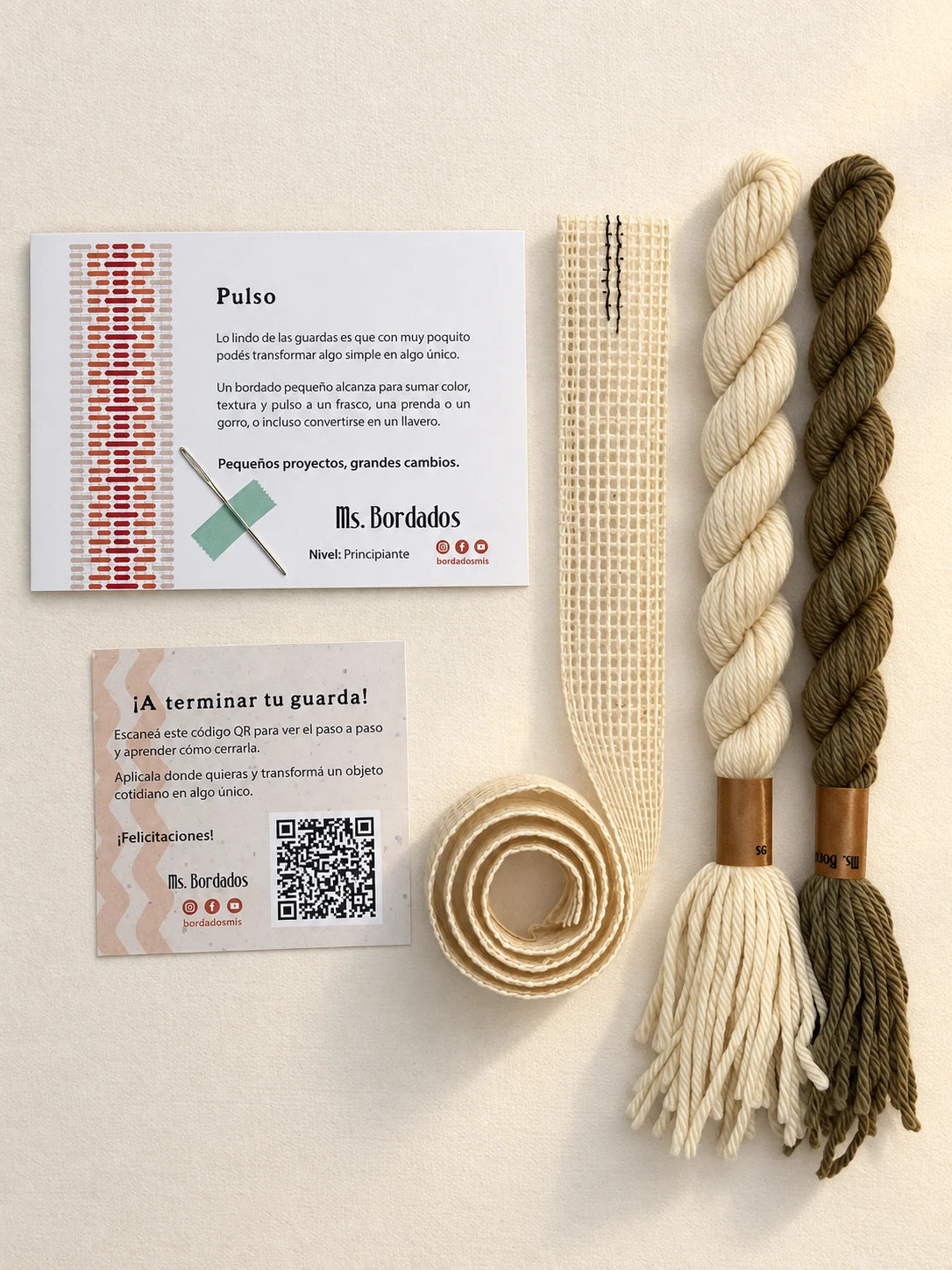 Componentes del Kit Franja Pulso Lino (formato Guarda larga): cañamazo de 75 × 5 cm, lanas 100% uruguayas en Crudo y Topo, aguja, manual impreso y tarjeta con el QR del video para terminar tu guarda — Ms. Bordados