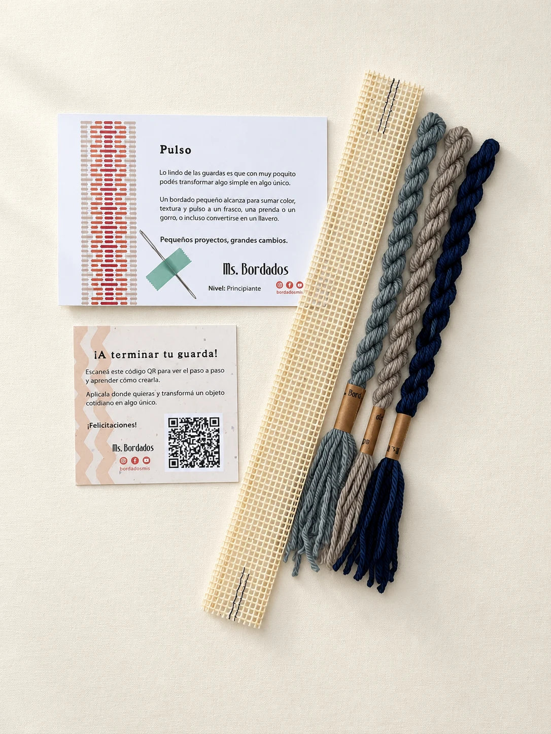 Componentes del Kit Franja Pulso Puerto (formato Guarda corta): cañamazo de 30 × 5 cm, lanas 100% uruguayas en Beige, Azul y Gris celeste, aguja, manual impreso y tarjeta con el QR del video para terminar tu guarda — Ms. Bordados
