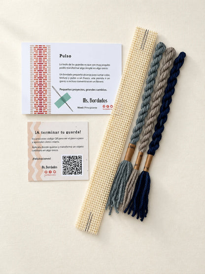 Componentes del Kit Franja Pulso Puerto (formato Guarda corta): cañamazo de 30 × 5 cm, lanas 100% uruguayas en Beige, Azul y Gris celeste, aguja, manual impreso y tarjeta con el QR del video para terminar tu guarda — Ms. Bordados