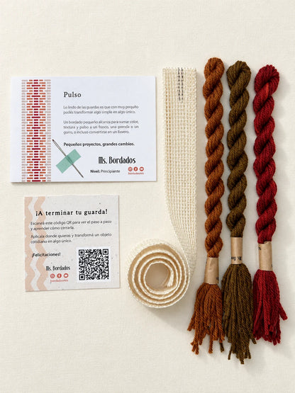 Componentes del Kit Franja Pulso Terracota (formato Guarda larga): cañamazo de 75 × 5 cm, lanas 100% uruguayas en Rojo ladrillo, Cobre y Tostado, aguja, manual impreso y tarjeta con el QR del video para terminar tu guarda — Ms. Bordados