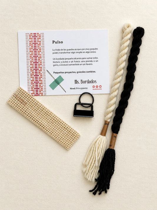 Componentes del Kit Franja Pulso Tinta (formato Llavero): cañamazo, lanas 100% uruguayas en Negro y Crudo, aguja, manual impreso y herraje del llavero — Ms. Bordados