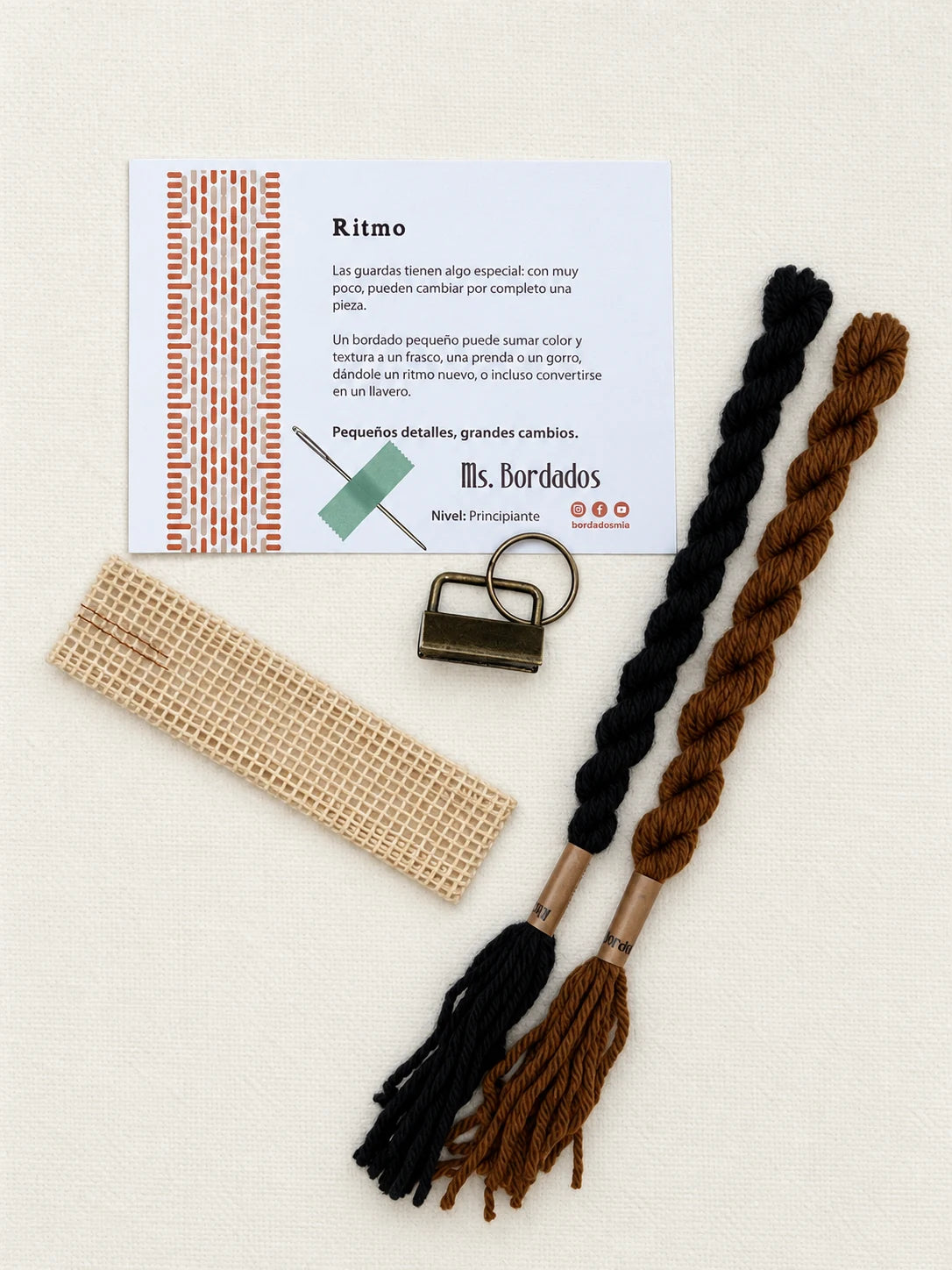 Componentes del Kit Franja Ritmo Café (formato Llavero): cañamazo, lanas 100% uruguayas en Tostado y Negro, aguja, manual impreso y herraje del llavero — Ms. Bordados