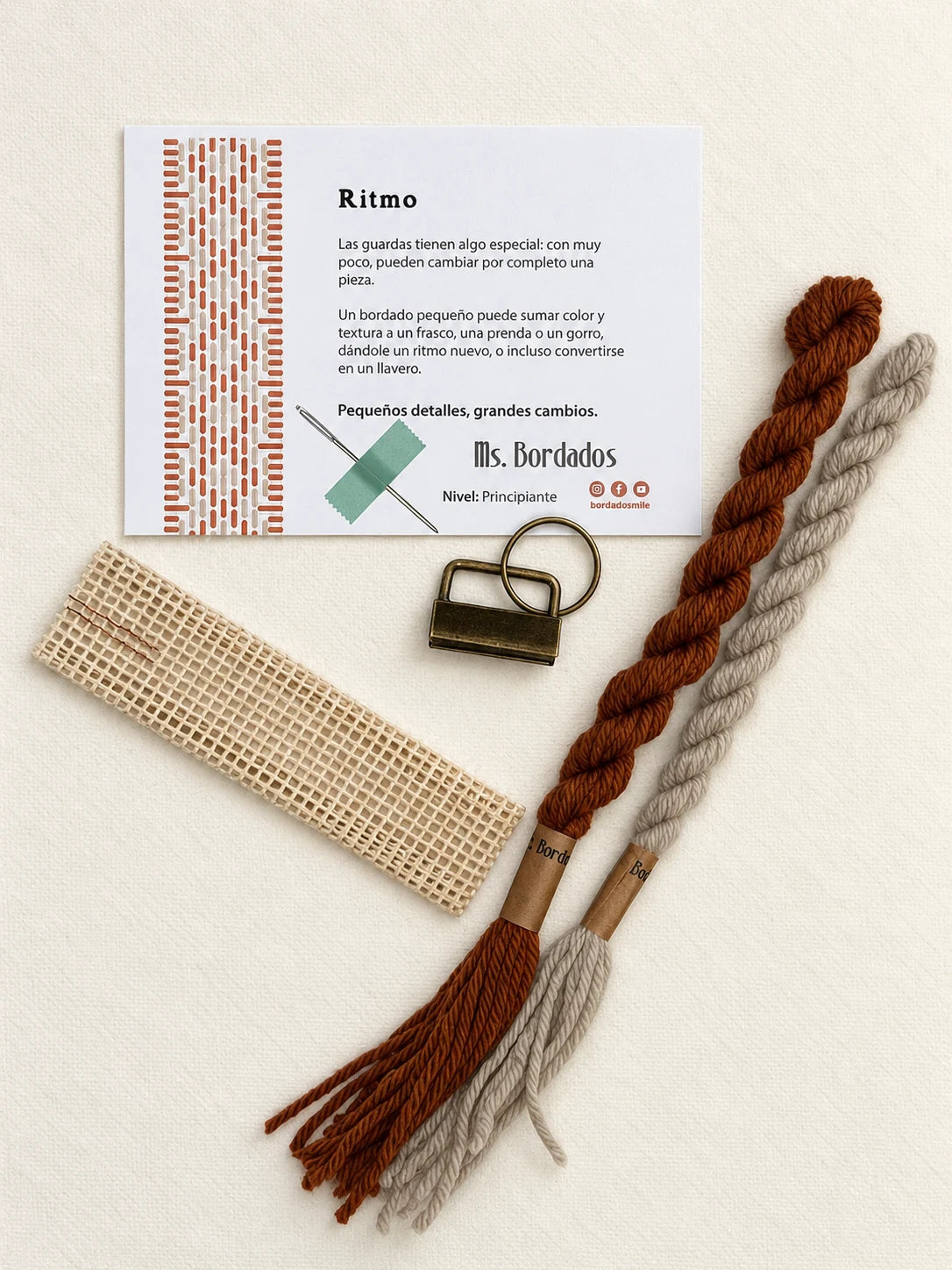 Componentes del Kit Franja Ritmo Cobre (formato Llavero): cañamazo, lanas 100% uruguayas en Beige y Cobre, aguja, manual impreso y herraje del llavero — Ms. Bordados