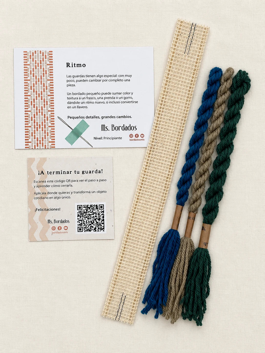 Componentes del Kit Franja Ritmo Pavo Real (formato Guarda corta): cañamazo de 30 × 5 cm, lanas 100% uruguayas en Azul eléctrico, Verde forestal y Taupe, aguja, manual impreso y tarjeta con el QR del video para terminar tu guarda — Ms. Bordados