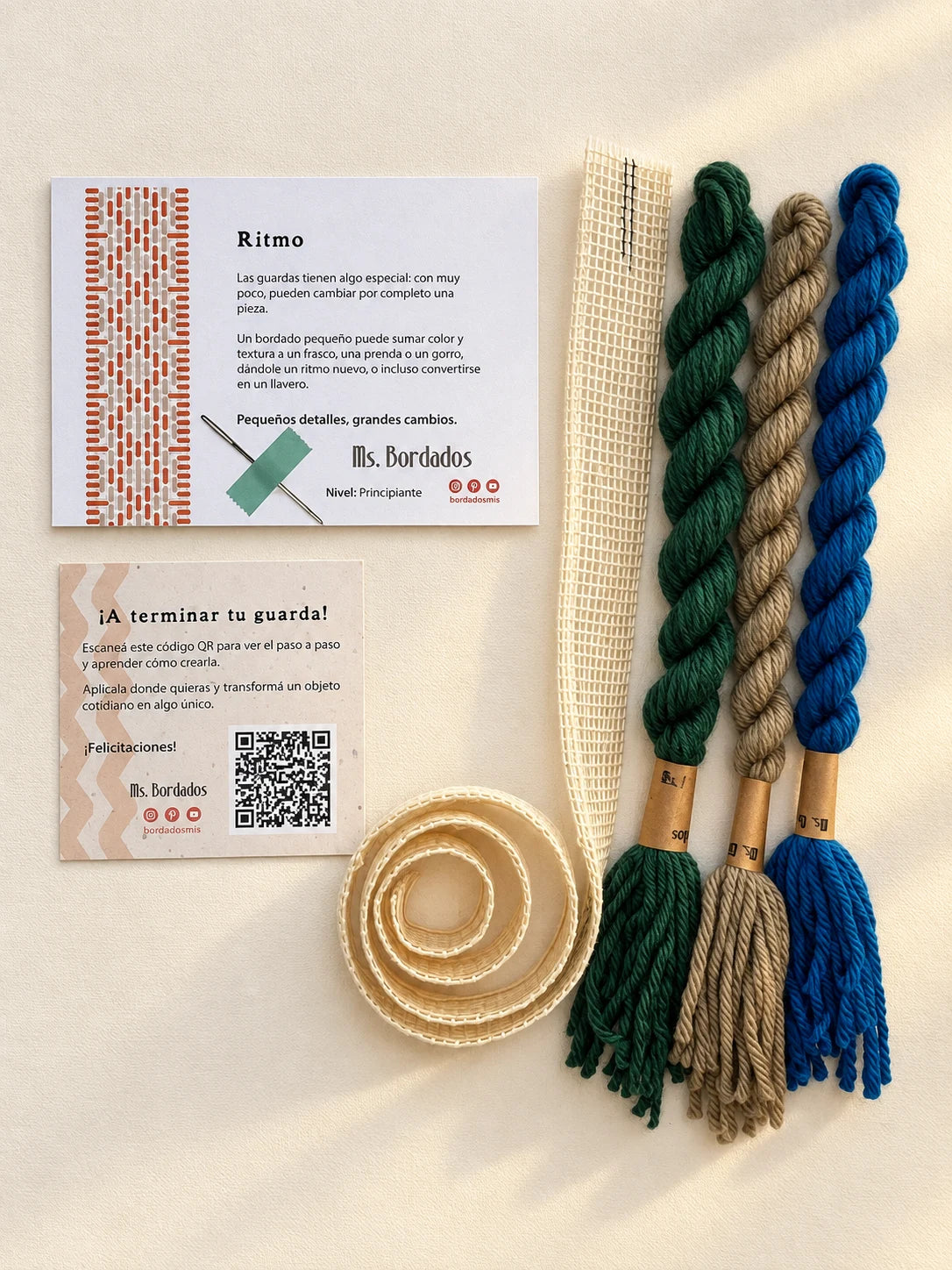Componentes del Kit Franja Ritmo Pavo Real (formato Guarda larga): cañamazo de 75 × 5 cm, lanas 100% uruguayas en Azul eléctrico, Verde forestal y Taupe, aguja, manual impreso y tarjeta con el QR del video para terminar tu guarda — Ms. Bordados