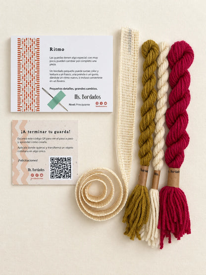 Componentes del Kit Franja Ritmo Vintage (formato Guarda larga): cañamazo de 75 × 5 cm, lanas 100% uruguayas en Magenta viejo, Oro viejo y Crudo, aguja, manual impreso y tarjeta con el QR del video para terminar tu guarda — Ms. Bordados