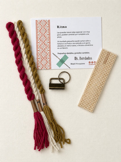 Componentes del Kit Franja Ritmo Vintage (formato Llavero): cañamazo, lanas 100% uruguayas en Magenta viejo, Oro viejo y Crudo, aguja, manual impreso y herraje del llavero — Ms. Bordados