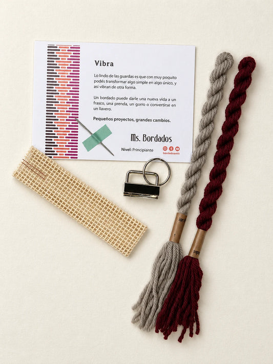 Componentes del Kit Franja Vibra Burdeos (formato Llavero): cañamazo, lanas 100% uruguayas en Bordeaux y Gris, aguja, manual impreso y herraje del llavero — Ms. Bordados