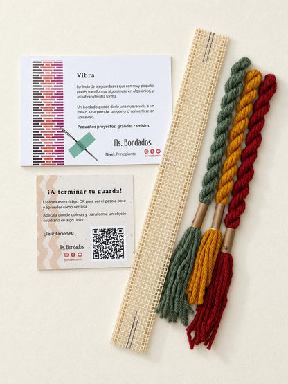 Componentes del Kit Franja Vibra Kilim (formato Guarda corta): cañamazo de 30 × 5 cm, lanas 100% uruguayas en Verde forestal, Rojo ladrillo y Amarillo, aguja, manual impreso y tarjeta con el QR del video para terminar tu guarda — Ms. Bordados