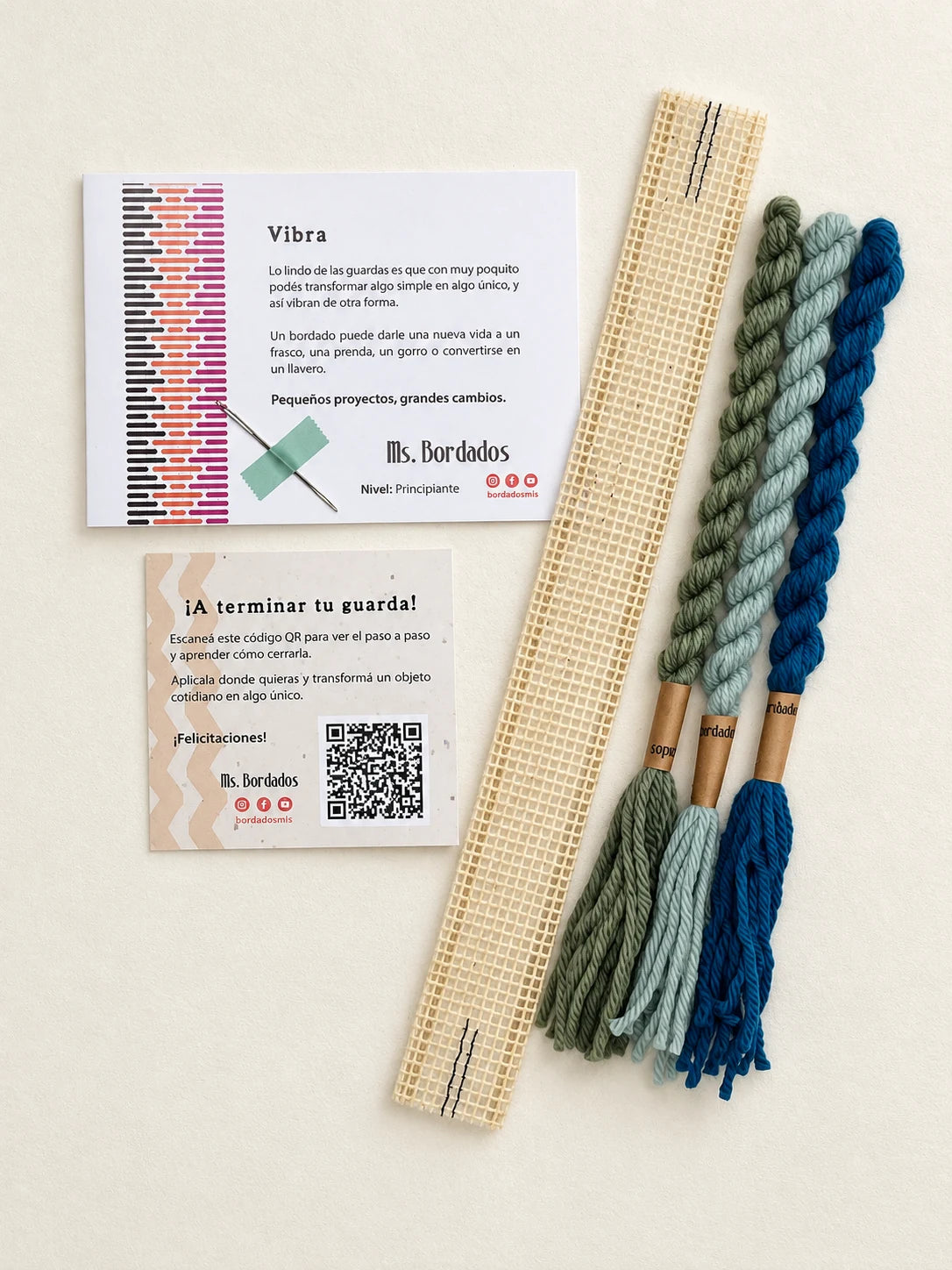 Componentes del Kit Franja Vibra Laguna (formato Guarda corta): cañamazo de 30 × 5 cm, lanas 100% uruguayas en Turquesa intenso, Celeste viejo y Verde bosque, aguja, manual impreso y tarjeta con el QR del video para terminar tu guarda — Ms. Bordados