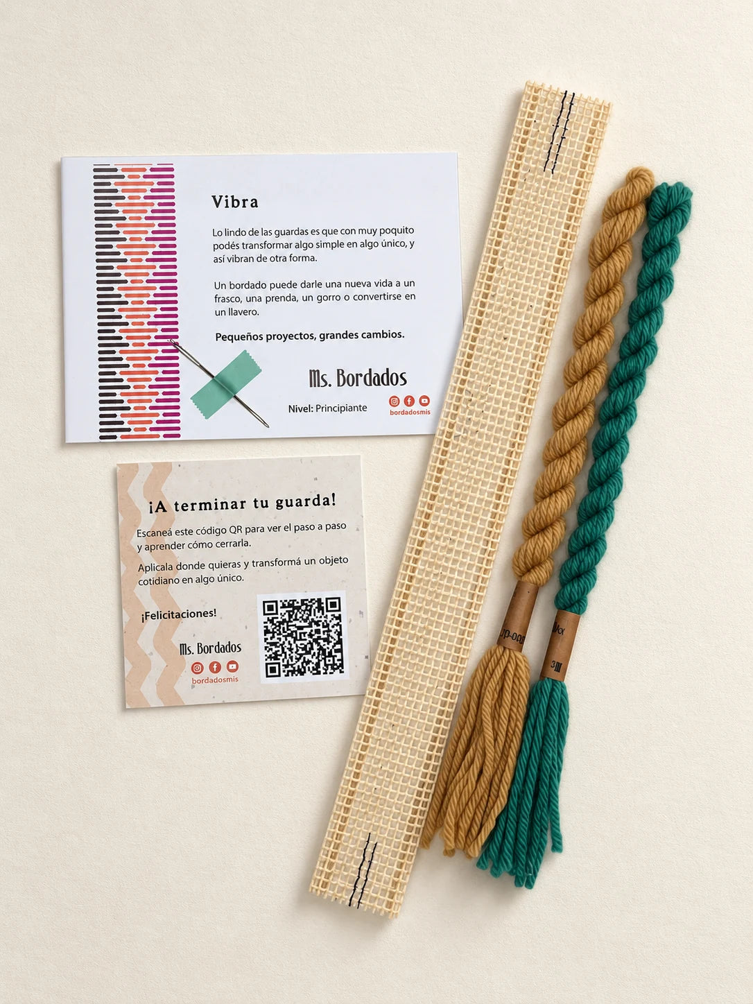 Componentes del Kit Franja Vibra Oliva (formato Guarda corta): cañamazo de 30 × 5 cm, lanas 100% uruguayas en Verde y Camel, aguja, manual impreso y tarjeta con el QR del video para terminar tu guarda — Ms. Bordados