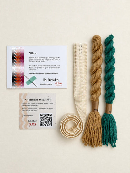 Componentes del Kit Franja Vibra Oliva (formato Guarda larga): cañamazo de 75 × 5 cm, lanas 100% uruguayas en Verde y Camel, aguja, manual impreso y tarjeta con el QR del video para terminar tu guarda — Ms. Bordados