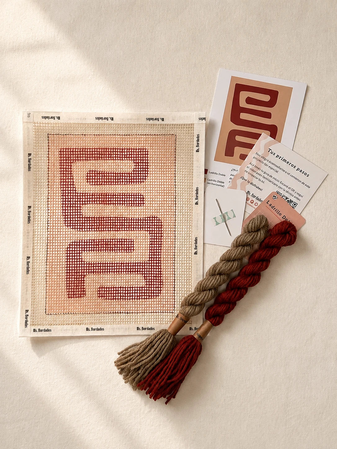 Componentes del Kit Cuadrito Kuba Kasai Arena: cañamazo con el diseño, lanas en rojo ladrillo y beige, aguja y tarjetas de puntadas — Ms. Bordados